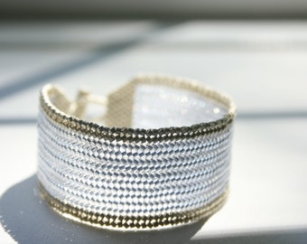 May include: A silver and gold beaded bracelet with a woven design.