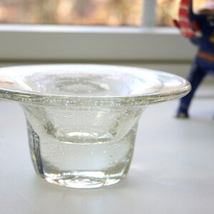 May include: A clear glass bowl with a wide rim and a textured surface. The bowl is filled with water and has small air bubbles trapped inside.