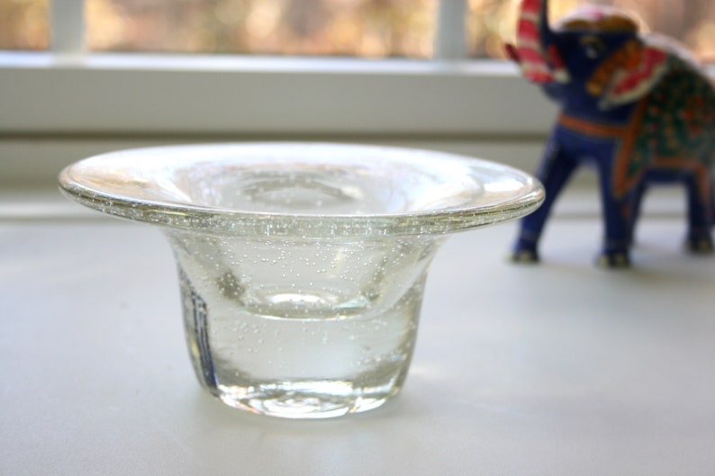 May include: A clear glass bowl with a wide rim and a textured surface. The bowl is filled with water and has small air bubbles trapped inside.