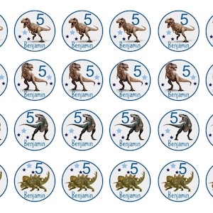 Könnte beinhalten: Vierundzwanzig runde Cupcake-Topper mit Dinosaurier-Motiv. Jeder Topper hat einen blauen Kreis mit weißem Hintergrund und die Zahl "5" in blauer Schrift. Der Dinosaurier ist ein Tyrannosaurus Rex oder ein Triceratops. Der Name "Benjamin" ist in blauer Schrift unter dem Dinosaurier gedruckt.