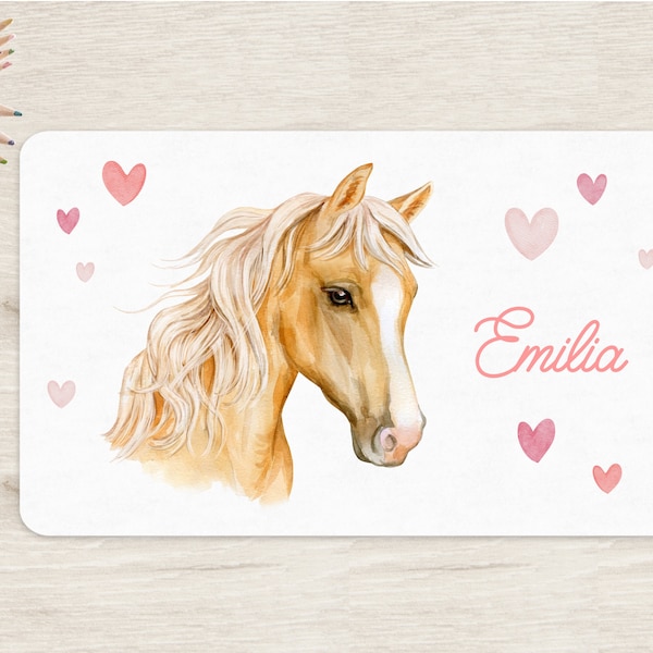 Pode incluir: Uma ilustração em aquarela de um cavalo marrom claro com uma crina e cauda loiras. O cavalo está olhando para a direita. O fundo é branco com corações rosa espalhados ao redor do cavalo. O nome "Emilia" está escrito em caligrafia rosa abaixo do cavalo.