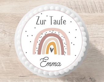 Op de afbeelding: Een witte cake met een ronde, eetbare afbeelding van een regenboog met een hart in het midden. De tekst "Zur Taufe" en "Emma" staat op de cake gedrukt.