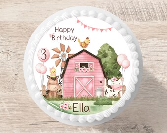 May include: A pink and white cake with a farm theme. The cake is decorated with a pink barn, a cow, a horse, a chicken, and a windmill. The cake also has a pink banner with the words "Happy Birthday" and the number "3". The cake is decorated with the name "Ella".