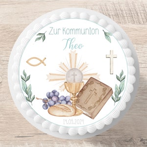 Op de afbeelding: Witte taarttopper met een aquarelontwerp met een kelk, een bijbel, druiven, brood en een kruis. De tekst "Zur Kommunion Theo 14.05.2024" staat op de topper gedrukt.