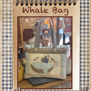 Puede incluir: Un bolso tote hecho a mano con un diseño de ballena. El bolso presenta un patrón a cuadros azul y blanco, un asa gris y un diseño de ballena con una corona. El texto "Whale Bag" está en la parte superior.