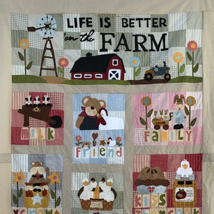 Può includere: Una trapunta colorata a patchwork con un tema da fattoria. La trapunta presenta un fienile rosso, un trattore e vari animali da fattoria. La trapunta è composta da quadrati con diversi motivi e colori. Il testo "Life is better on the farm" è scritto in lettere nere nella parte superiore della trapunta.
