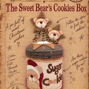 May include: A cylindrical fabric container titled The Sweet Bear's Cookies Box, featuring a beige bear wearing a red Santa hat. The lid is dark gray with felt stars and two bear heads on sticks. Text includes "Sugar Cookie" and "A jar full of sweet Christmas wishes."