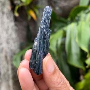 May include: A dark blue and green crystal with a pointed tip. The crystal is made up of many small, thin crystals that are clustered together.