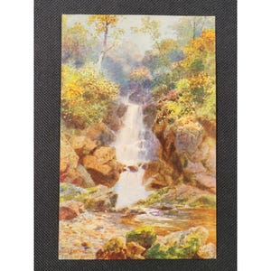 May include: A vintage postcard featuring a watercolor painting of a waterfall cascading down rocky cliffs. The artwork showcases vibrant autumn foliage in shades of yellow and orange, with a serene stream at the base. The text "Falls of Anico" is visible.