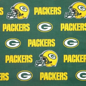 Pode incluir: Tecido verde com um padrão repetido de capacetes de futebol americano amarelos, a palavra "PACKERS" em letras amarelas e o logotipo "G" da equipa em branco com contorno amarelo. Um têxtil com tema desportivo.
