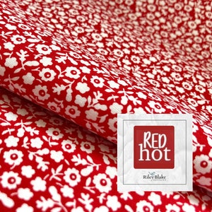 Op de afbeelding: Rode stof met een wit bloemenpatroon. De stof is doormidden gevouwen en de tekst "Red Hot" is zichtbaar in de rechterbenedenhoek.