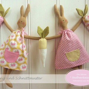 Puede incluir: Muñecas de conejito de tela hechas a mano con accesorios de zanahoria. Los conejitos visten vestidos con estampados florales y de lunares, y tienen bolsillos rosas. La imagen incluye texto en alemán: "Hasengirlande" y "Die kleine Stoffwerkstatt".