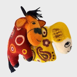 May include: Two felted animal figures. The left figure is orange with a red body featuring concentric circle patterns and black accents. The right figure is yellow with a cream-colored face, brown floral and paisley patterns, and black eye details.