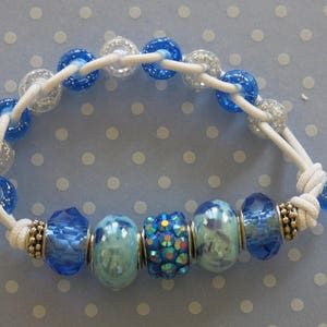 May include: A blue and white beaded bracelet with a silver charm and blue and white glass beads.