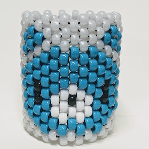May include: A blue and white beaded bracelet with a black eye design. The bracelet is made of small, round beads that are strung together on a string.