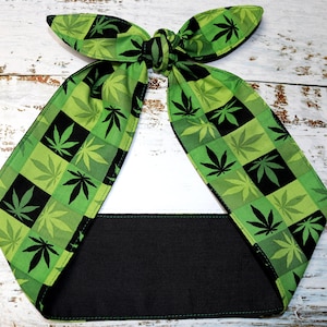 May include: Green and black headband with a checkered pattern of marijuana leaves. The headband is tied in a knot at the top.
