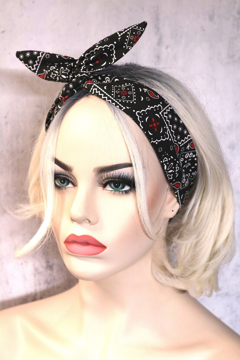May include: A black and white bandana headband with a red paisley pattern. The headband is tied in a knot at the top of the head.