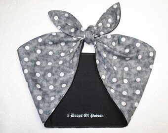 May include: A gray and white polka dot bandana with a black backing. The bandana is tied in a bow at the top and has the text "3 Drops of Poison" printed on the back.