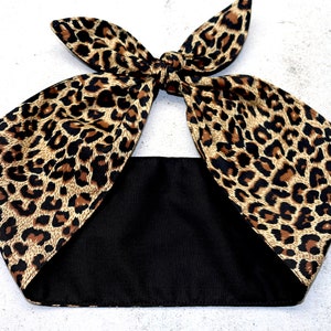 Può includere: Un cerchietto con stampa leopardata e retro in tessuto nero. Il cerchietto è legato in un fiocco nella parte superiore.