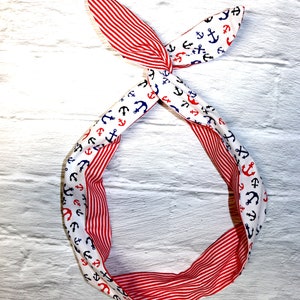 May include: Red and white striped headband with a white fabric on the other side featuring a navy blue and red anchor pattern.