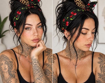 May include: A black headband with a cherry and leopard print design. The headband is tied in a bow on top of the head. The person in the image is wearing a black tank top and has tattoos on their arms and neck.