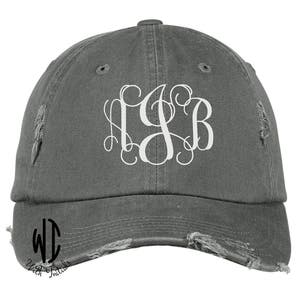 May include: A gray distressed baseball cap with a white monogram of the letters "LSB" on the front. The cap has a curved brim and a distressed look.