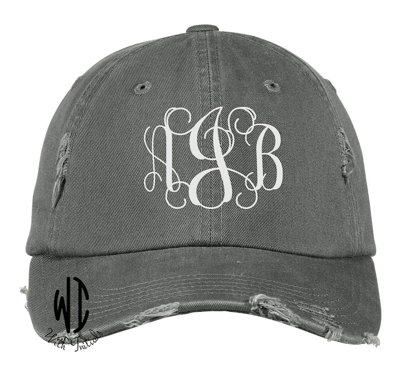 May include: A gray distressed baseball cap with a white monogram of the letters "LSB" on the front. The cap has a curved brim and a distressed look.