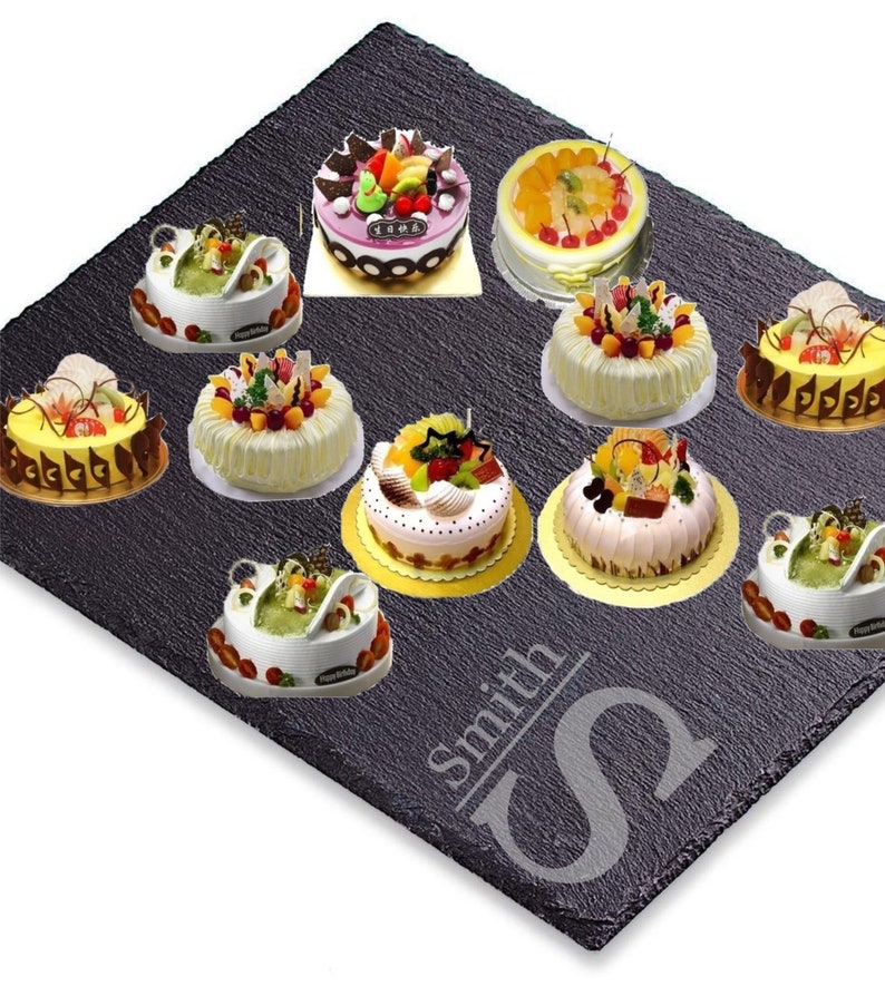 Puede incluir: Surtido de diez pasteles decorados con diferentes coberturas de fruta, presentados en una bandeja de servicio de pizarra negra con la palabra "Smith" y una letra "S" estilizada grabada en la superficie.