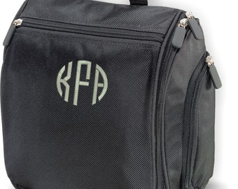 Puede incluir: Bolsa de aseo de viaje negra con un bolsillo con cremallera y un monograma "KFA" en gris claro.