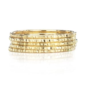 May include: Set of six gold hammered stacking rings. The rings are thin and delicate, with a textured hammered finish.