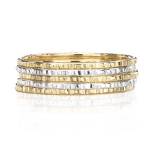 May include: Set of five thin gold and silver stacking rings with a hammered texture.