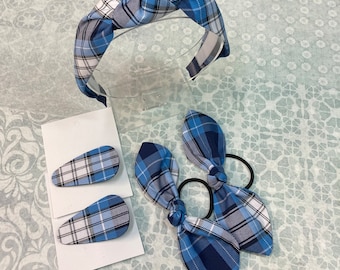 May include: A set of blue and white plaid hair accessories including a headband, two hair clips, and a hair tie. The headband is knotted and the hair tie is tied into a bow.