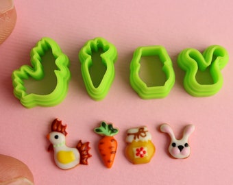 Peut inclure: Ensemble de cinq emporte-pièces en plastique vert en forme de poussin, de carotte, de pot et de lapin, et cinq biscuits décorés en forme de poussin, de carotte, de pot et de lapin.