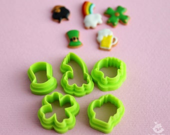May include: A set of green plastic cookie cutters shaped like a leprechaun hat, shamrock, beer mug, and other St. Patrick's Day themed designs.