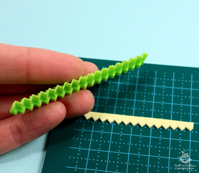 Może przedstawiać: Dwa zielone plastikowe narzędzia z falistym brzegiem. Narzędzia znajdują się na zielonej macie do cięcia z siatką.