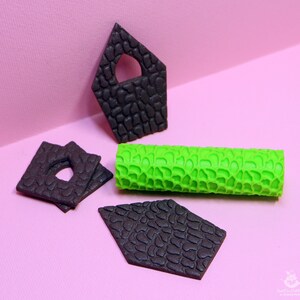 Puede incluir: Un conjunto de cuatro piezas de fondant negro con textura de piedra, con forma de casa, rect&aacute;ngulo y dos diamantes. Tambi&eacute;n se incluye un rodillo de fondant verde con textura de piedra.
