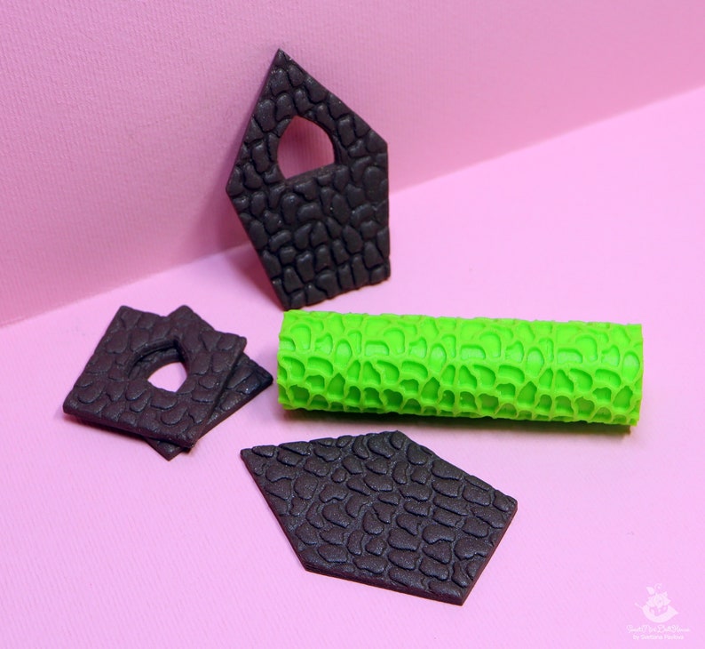 Puede incluir: Un conjunto de cuatro piezas de fondant negro con textura de piedra, con forma de casa, rect&aacute;ngulo y dos diamantes. Tambi&eacute;n se incluye un rodillo de fondant verde con textura de piedra.