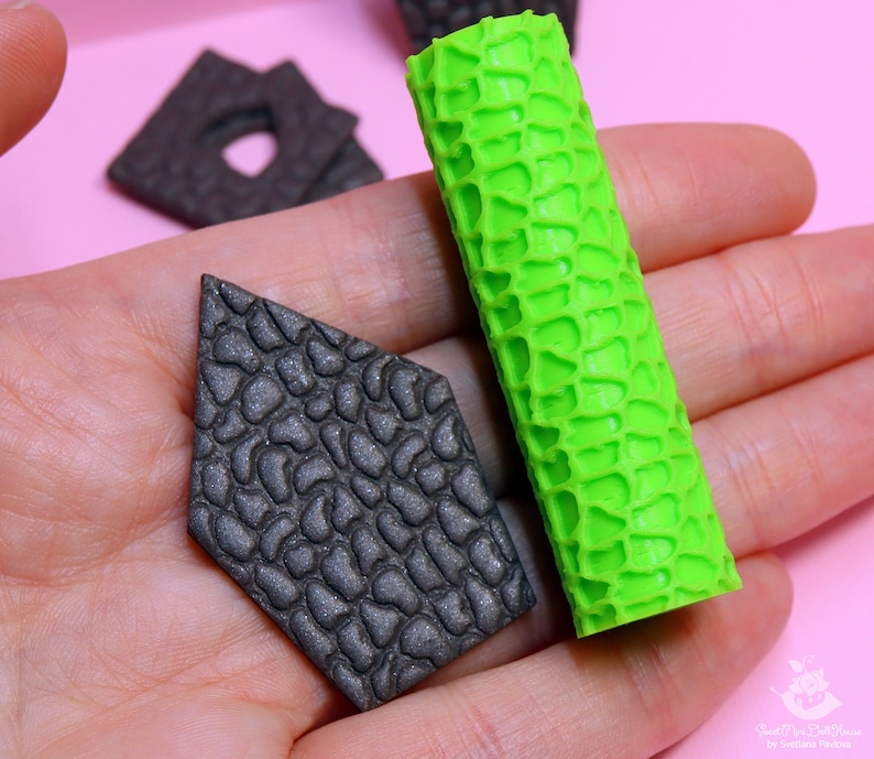 Puede incluir: Dos herramientas de decoraci&oacute;n de pasteles de silicona, una es un rodillo texturizado verde y la otra es una forma de diamante texturizada negra.