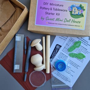 Könnte beinhalten: Ein DIY-Starterset für Miniatur-Töpferei und Geschirr von Sweet Mini Doll House, bestehend aus einem Karton, Holzformen, grauen Modellierwerkzeugen, einer Metallklinge, grünen Blattformen, einem blauen runden Ausstecher und gedruckten Anleitungen.