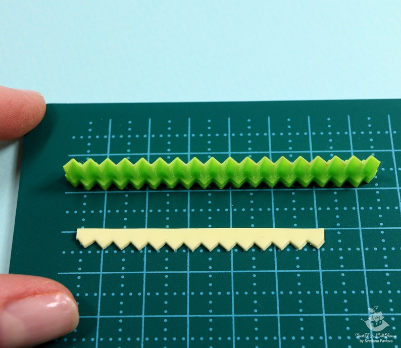 Może przedstawiać: Dwa paski dekoracyjnego lukru, jeden zielony, a drugi ż&oacute;łty, z falistym brzegiem. Lukier leży na zielonej macie do krojenia.