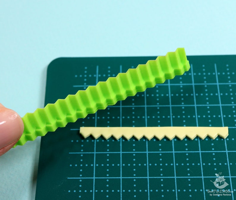 Może przedstawiać: Zielone plastikowe narzędzie z wzorem zygzakowatym, używane do tworzenia ozdobnych krawędzi na fondancie lub innych jadalnych materiałach. Na zdjęciu widoczna jest r&oacute;wnież mniejsza, ż&oacute;łta wersja narzędzia.