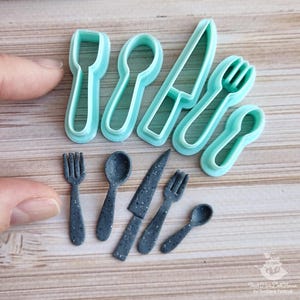 Può includere: Una collezione di utensili da cucina in miniatura, tra cui forchette, cucchiai e coltelli. Il set presenta versioni grigie piene e versioni con contorno blu chiaro. Gli utensili sono progettati per l'artigianato o le case delle bambole.