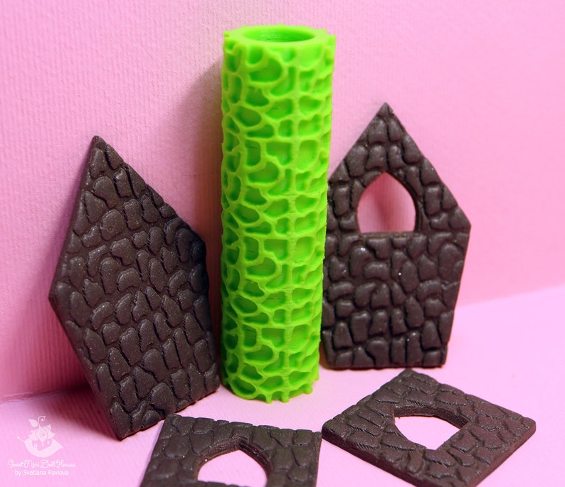 Puede incluir: Un conjunto de cinco herramientas para decorar pasteles, que incluyen un rodillo verde y cuatro piezas de fondant marr&oacute;n con ventanas recortadas. Las herramientas se utilizan para crear una textura de piedra en los pasteles.