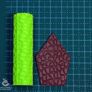 Puede incluir: Dos rodillos de silicona para hornear, uno verde y otro marr&oacute;n. El rodillo verde tiene una superficie texturizada que se asemeja a la piedra. El rodillo marr&oacute;n tiene forma de casa y tiene una textura de piedra similar.