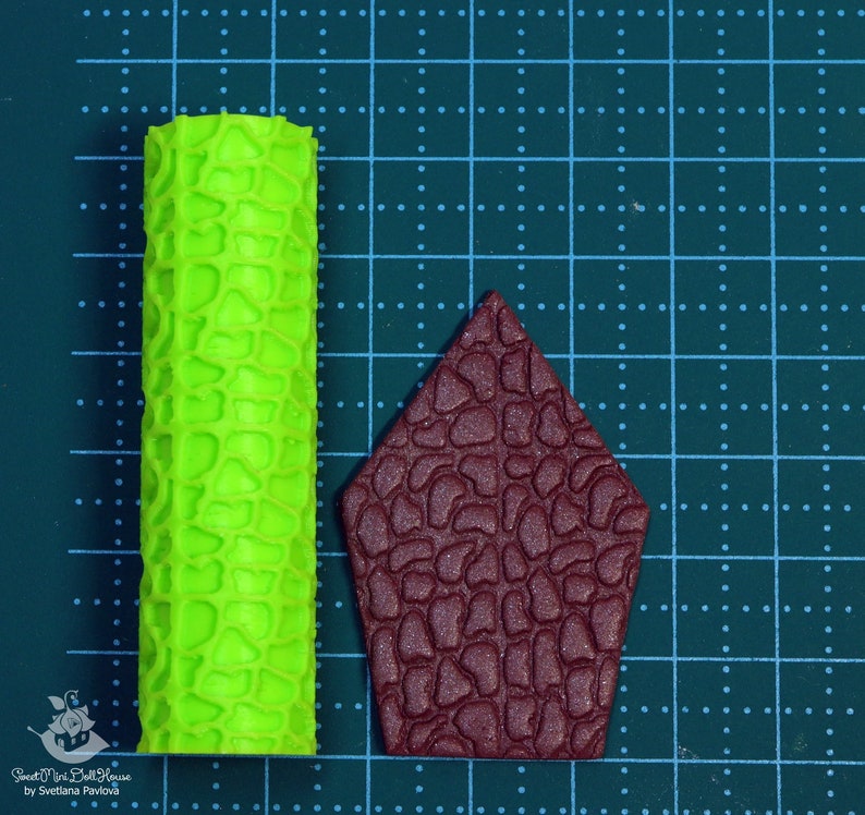 Puede incluir: Dos rodillos de silicona para hornear, uno verde y otro marr&oacute;n. El rodillo verde tiene una superficie texturizada que se asemeja a la piedra. El rodillo marr&oacute;n tiene forma de casa y tiene una textura de piedra similar.