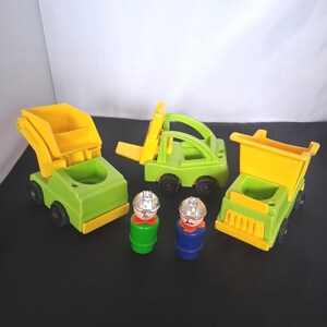 May include: A collection of vintage toy construction vehicles in green and yellow, including a dump truck, a forklift, and a flatbed truck. Two small toy construction worker figures are also present, with silver helmets and colorful outfits. The toys are made of plastic.
