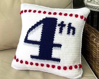 May include: White crocheted cushion with a blue "4th" design and red pom-poms around the edge.