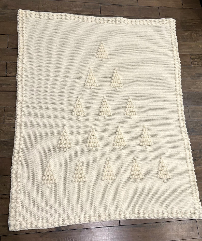 May include: A white crocheted blanket with a design of multiple white crocheted Christmas trees.