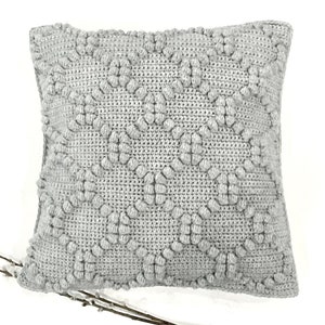 May include: A gray, textured, square pillow with a raised diamond pattern. The pillow is made of a soft, plush fabric.