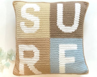 May include: A crocheted pillow with the word "SURF" spelled out in white yarn on a beige, brown, and light blue background.